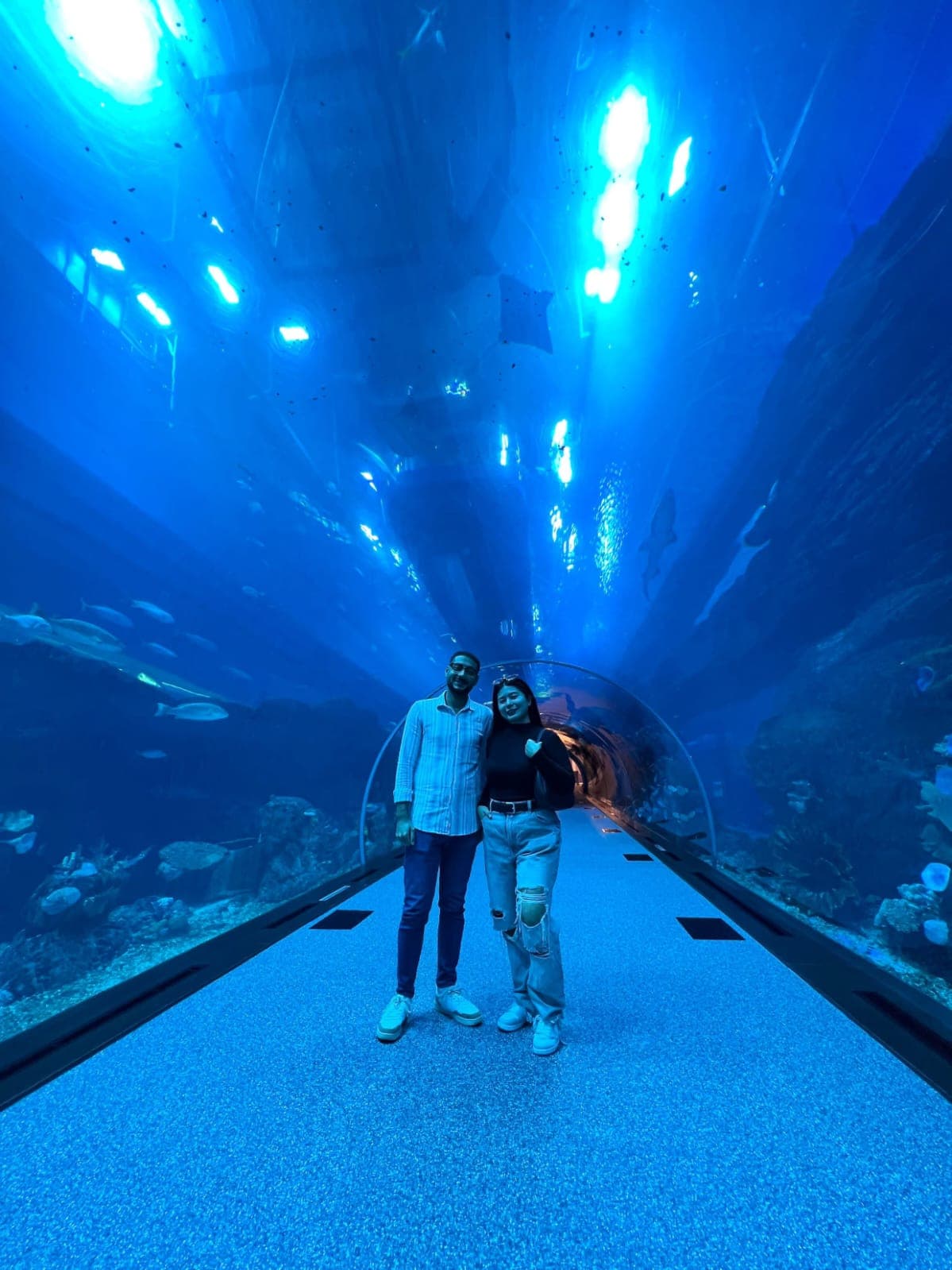 Kim and me standing close together in the glowing blue tunnel at Dubai Aquarium