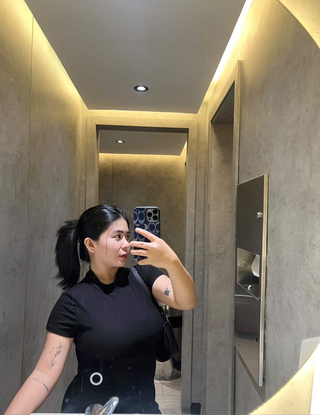 Kim taking a mirror selfie, hair in a ponytail, in soft golden light